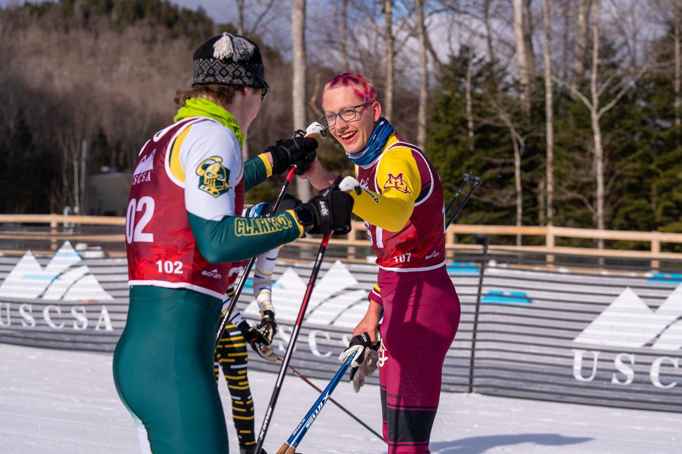 Wesley Sumner of Colorado Mesa University shares a post-race fist bump with a Clarkson University skier after winning the 15 km freestyle at USCSA National Championships in Lake Placid.